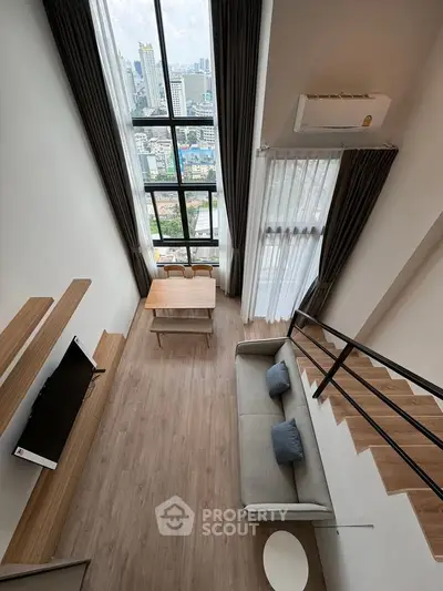 Stunning loft apartment with floor-to-ceiling windows and city view, featuring modern decor and open living space.