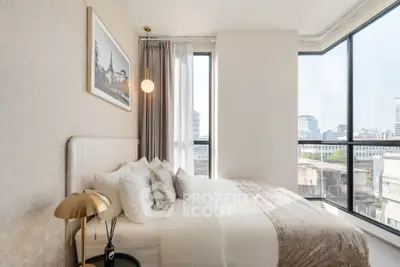 Elegant bedroom with large windows offering stunning city views and modern decor.
