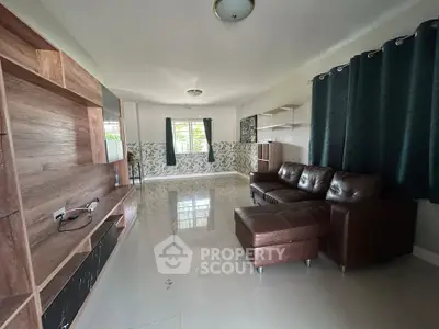 Spacious living room with modern leather sofa and entertainment unit, featuring large windows and elegant curtains.