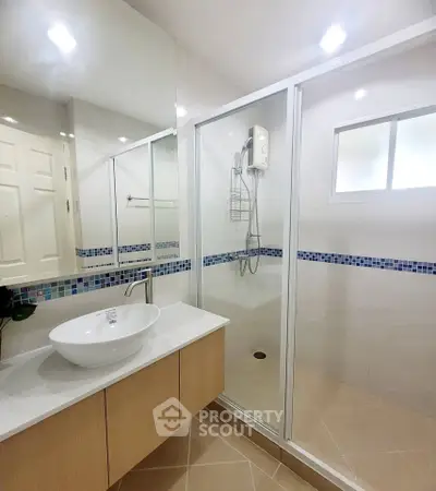 Modern bathroom with glass shower enclosure and stylish sink in a contemporary home.
