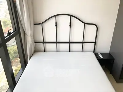 Modern bedroom with large window and stylish metal bed frame, offering a bright and airy atmosphere.