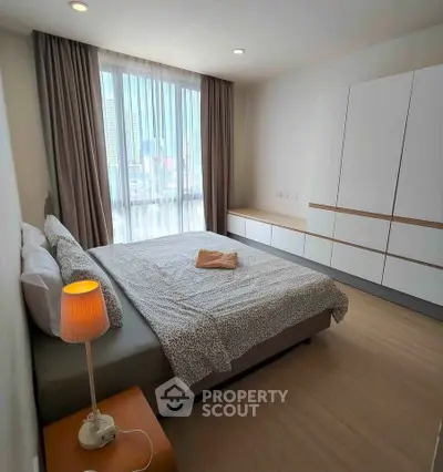 Modern bedroom with city view, featuring stylish furniture and natural light.