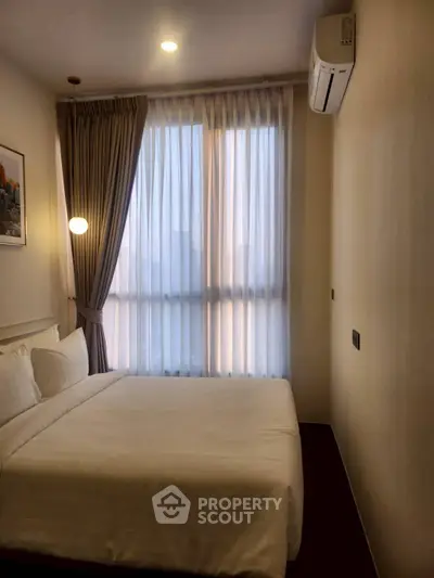 Cozy bedroom with modern decor and large window for natural light.