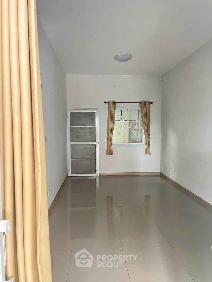 Spacious empty room with glossy tiled floor and large window, perfect for customization.
