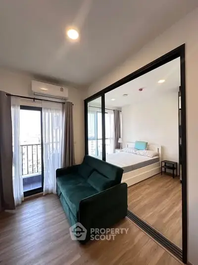 Modern apartment with glass partitioned bedroom and cozy living area, featuring a balcony with city views.