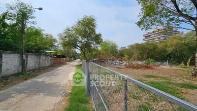 Vacant land with potential for development in a serene neighborhood, surrounded by greenery and a paved road.