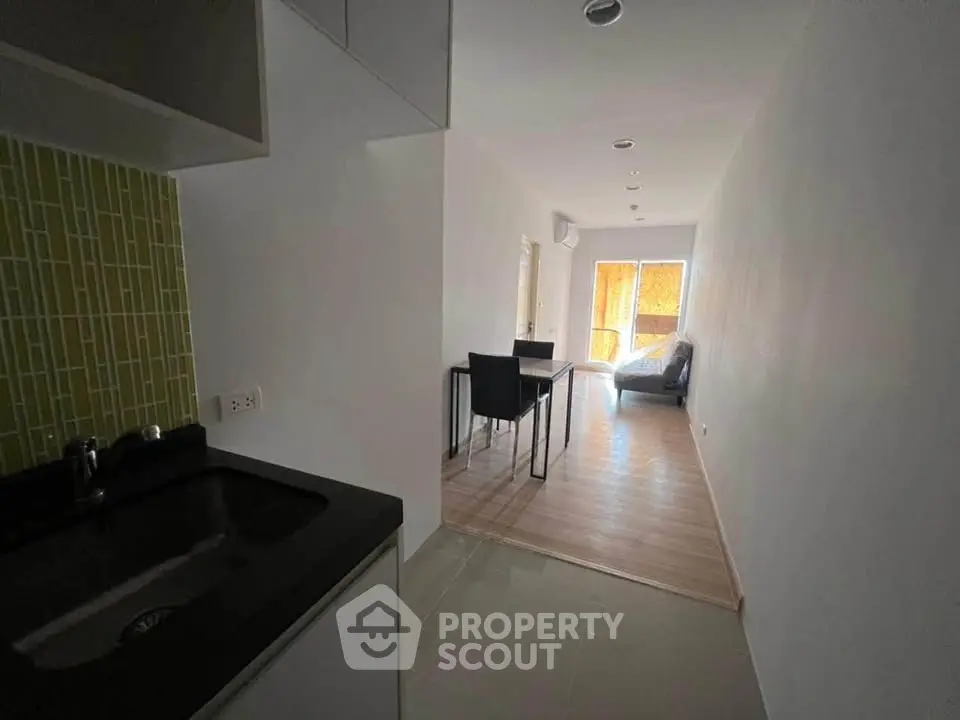 Modern apartment interior with sleek kitchen and cozy living area, featuring stylish furniture and natural light.