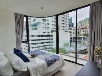 Modern bedroom with floor-to-ceiling windows offering stunning city views in a high-rise apartment.