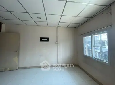 Spacious empty room with large window and tiled floor, ideal for customization.