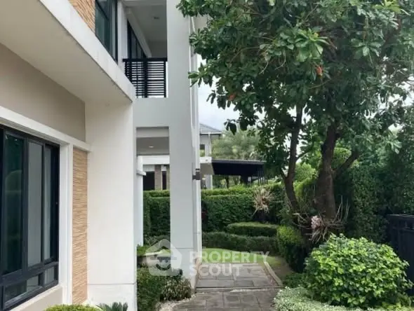 Charming garden path leading to a modern home entrance, surrounded by lush greenery.