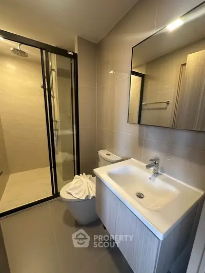 Modern bathroom with sleek fixtures and spacious shower in contemporary apartment.