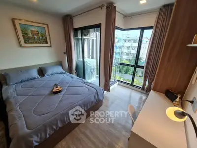 Modern bedroom with large windows and balcony view, featuring stylish decor and natural light.