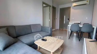 Modern living room with gray sofa and dining area in stylish apartment