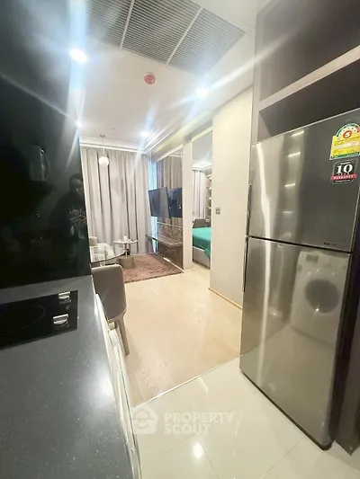 Modern open-layout kitchen with sleek appliances and cozy living area in a stylish apartment.