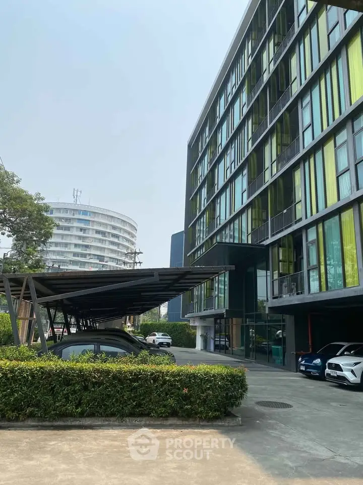 Modern apartment building with parking area and lush greenery, showcasing urban living.