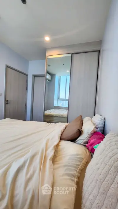 Cozy bedroom with mirrored closet and plush bedding in modern apartment