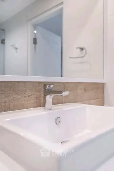 Modern bathroom sink with sleek faucet and wooden backsplash