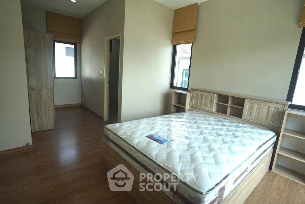 Spacious bedroom with wooden flooring and large windows in modern apartment