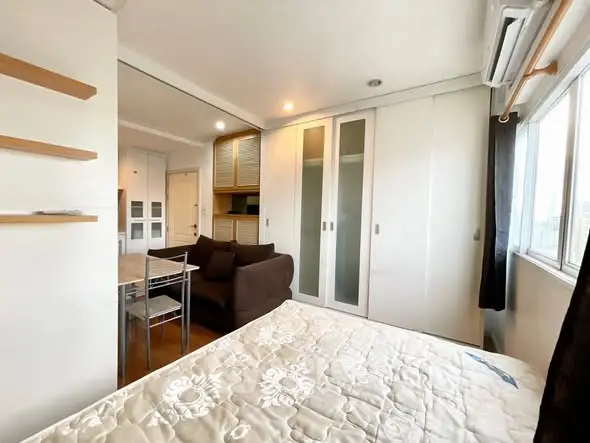 Modern bedroom with large windows and cozy seating area in a stylish apartment.