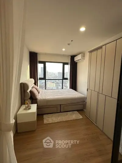 Modern bedroom with city view, featuring elegant decor and ample natural light.
