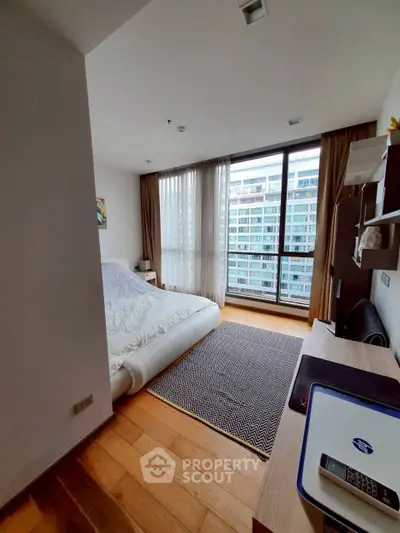 Modern bedroom with large window and city view, featuring cozy bed and stylish decor.