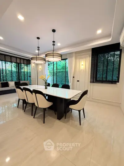 Elegant dining room with modern lighting and large windows overlooking greenery.