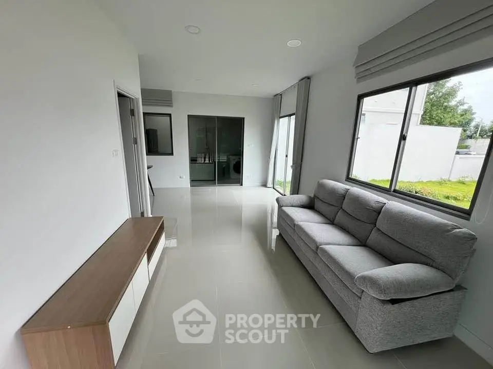 Modern living room with sleek furniture and large windows offering natural light.