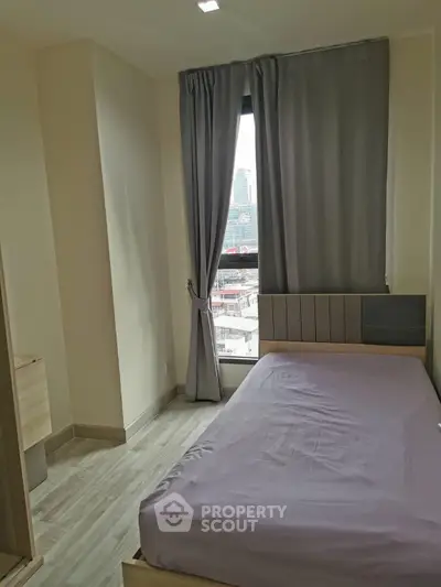 Cozy bedroom with city view, featuring modern furnishings and natural light.