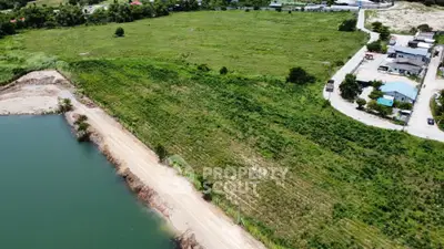 Expansive aerial view of prime real estate land near a serene water body, ideal for development.