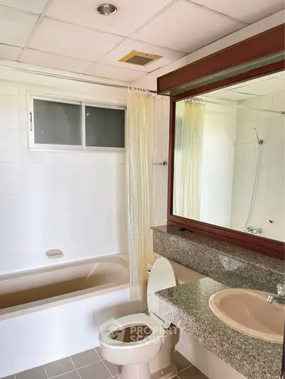 Spacious bathroom with bathtub and large mirror in modern apartment.