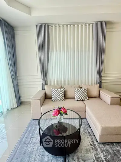 Elegant living room with modern sofa, stylish curtains, and chic glass coffee table.