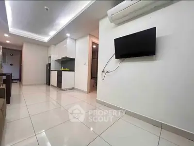 Modern open-layout living room with sleek kitchen and wall-mounted TV in a stylish apartment.
