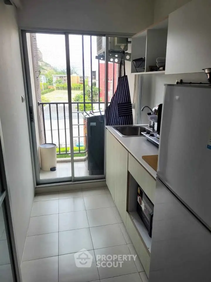 Compact kitchen with balcony view, featuring modern appliances and sleek design.