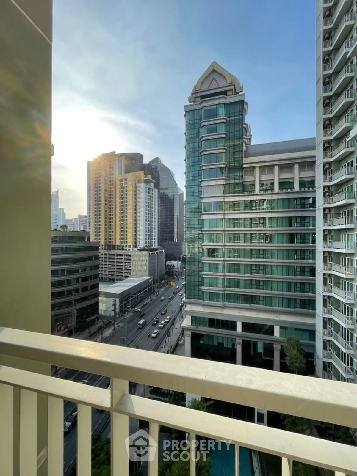 Stunning city view from a high-rise balcony overlooking urban skyline at sunset.