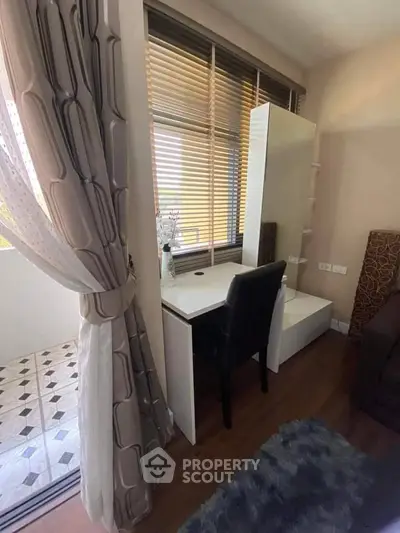 Cozy bedroom corner with desk and chair near window and balcony access.