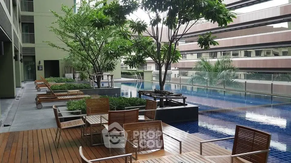 Luxurious poolside area with modern wooden deck and lush greenery in a contemporary building.