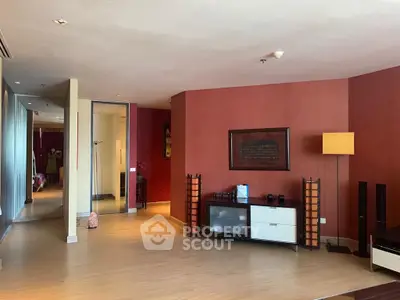 Spacious living room with modern decor and warm red accent walls, perfect for relaxation and entertainment.