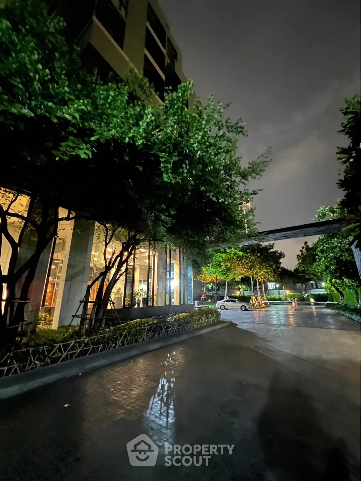 Elegant nighttime exterior view of modern building with lush greenery and ambient lighting.