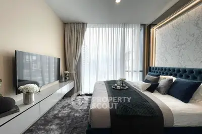 Luxurious modern bedroom with plush bed and large TV, featuring elegant decor and natural light.