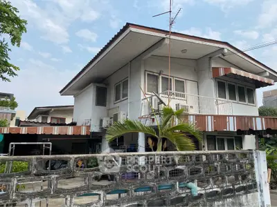 Charming two-story house with unique architectural design and lush greenery