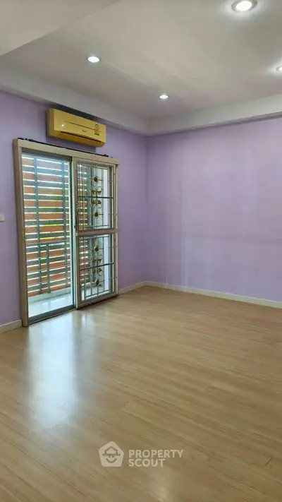 Spacious room with wooden flooring and large window, perfect for a cozy living space.