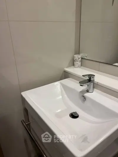Modern bathroom with sleek white sink and elegant fixtures.