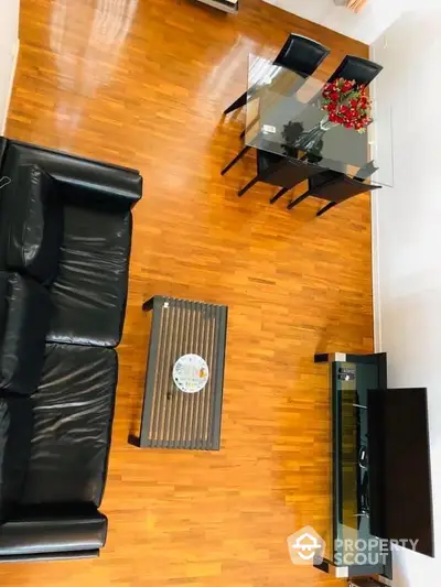 Inviting living room with polished hardwood floors, elegant glass dining table, and plush leather sofa, perfect for urban living.