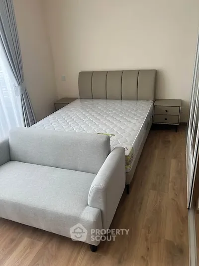 Modern bedroom with stylish bed and cozy sofa, featuring elegant wooden flooring and natural light.