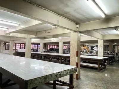 Spacious industrial workspace with large tables and ample lighting, ideal for manufacturing or creative projects.