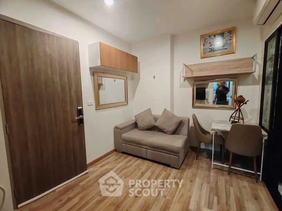 Cozy living room with modern decor and wooden flooring, featuring a compact sofa and dining area.