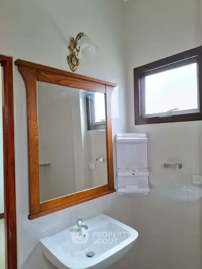 Charming bathroom with elegant wooden mirror and modern fixtures, perfect for a cozy home.