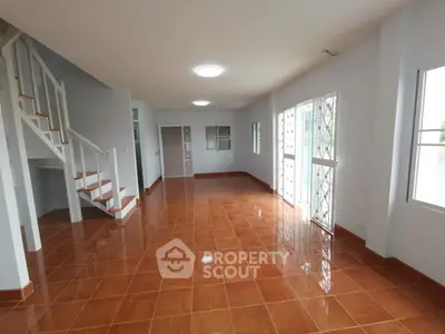 Spacious open-plan living room with tiled flooring and natural light