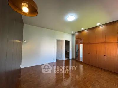 Spacious bedroom with wooden flooring and built-in wardrobes, perfect for modern living.