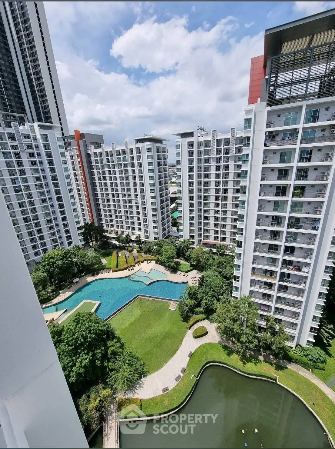 Stunning aerial view of modern apartment complex with pool and lush gardens, perfect for urban living.